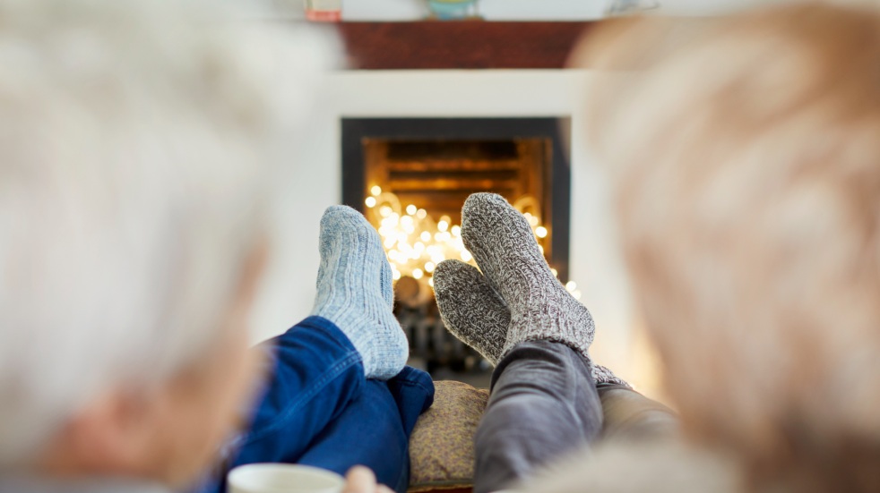 mature couple sitting by fireplace in socks